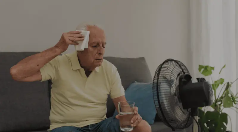 Personne âgée se rafraîchissant devant un ventilateur pendant une canicule
