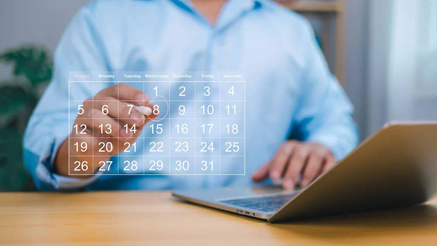 A calendar overlaid in front of a staff member working on his laptop