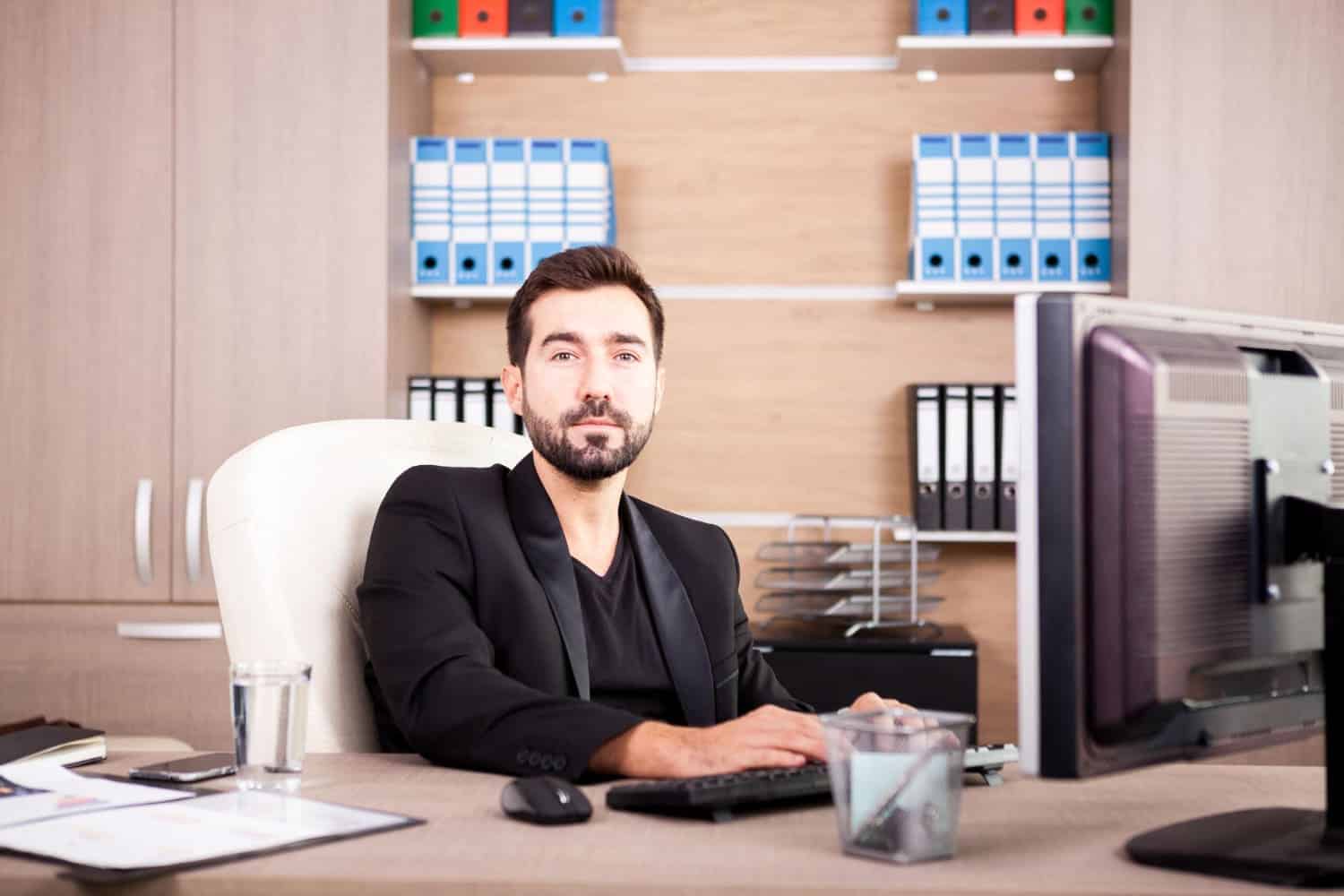 A staff member at his desk, surrounded by binders of administrative files