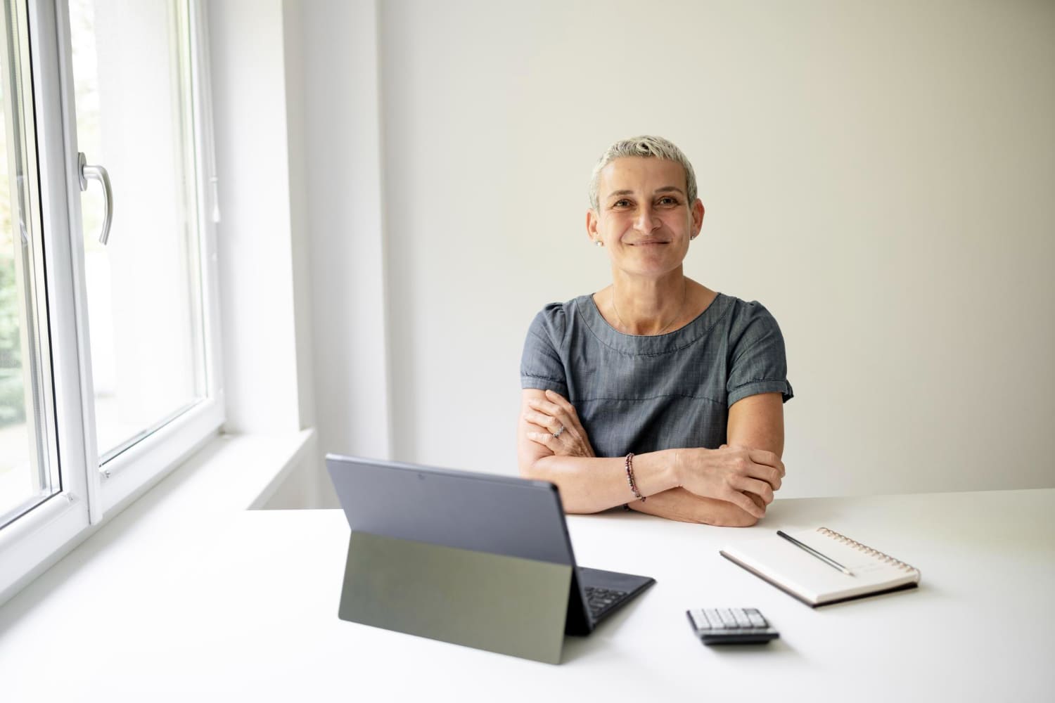 A smiling local government staff member at her desk, in front of her tablet