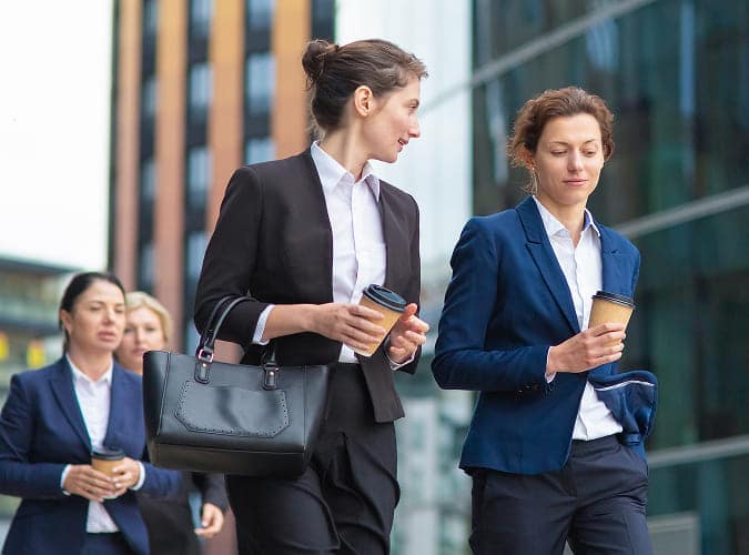 Des agentes échangent en marchant, un café à la main
