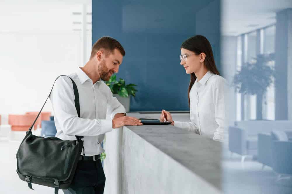 A resident is welcomed at the front desk by a staff member