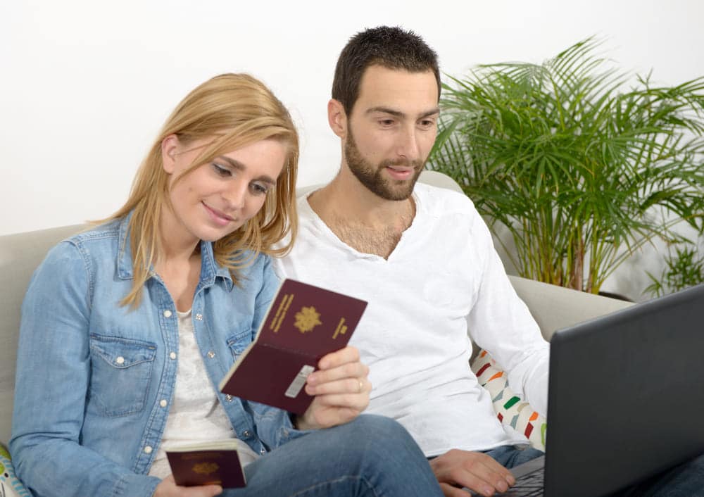 Un couple remplit sa pré-demande de passeport en ligne, passeport en main