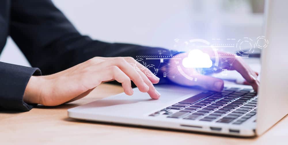 Des mains sur le clavier d’un ordinateur portable, sous un nuage de données chiffrées